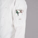 A Mercer Culinary white chef coat with red piping, pockets, and a pen holder.