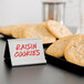 A plate of cookies with a white Tablecraft Tabletop Tent sign holding a card that says "rainbow cookies" on it.