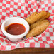 A plate of fried food with a bowl of red sauce.