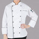 A woman wearing a Mercer Culinary white chef jacket with black piping.