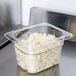 A Cambro clear plastic food pan filled with food on a counter.