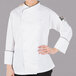 A woman wearing a white Mercer Culinary chef jacket with black piping.