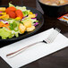A Libbey stainless steel dessert fork on a plate of salad with croutons and tomatoes.
