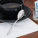 A black cup on a saucer with a spoon and a tea bag.
