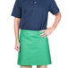 A man wearing a green Intedge waist apron with his hands on his hips.