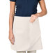 A woman wearing an ivory Intedge waist apron with a pocket.