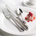 A white plate with a Libbey stainless steel salad fork, spoon, and knife on it.