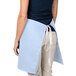 A woman wearing an Intedge light blue waist apron with a pocket.