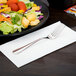 A Libbey stainless steel salad fork on a plate of salad with croutons and tomatoes.