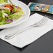 A plate of salad and a Libbey Aspen stainless steel salad fork on a white napkin.