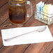 A Libbey stainless steel iced tea spoon on a napkin next to a glass of iced tea.