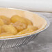 An apple pie in a D&W Fine Pack aluminum foil pie pan on a bakery counter.