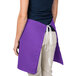 A woman wearing a purple Intedge waist apron with a white belt.