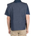The back of a man wearing an Intedge denim cobbler apron over a blue vest.