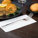 Libbey stainless steel European dinner fork on a napkin next to a plate of food.