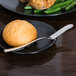 A Libbey stainless steel butter spreader on a plate with food.