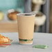 A close-up of an EcoChoice Double Wall Kraft paper hot cup filled with coffee on a table with a croissant.