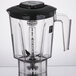 A clear Waring blender jar with a black lid and black handle.