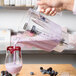 A person pouring purple liquid into a Waring blender.
