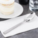 A Libbey stainless steel dessert spoon on a napkin next to a cake.