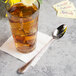 A glass of iced tea with a lemon wedge and a Libbey stainless steel iced tea spoon.