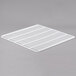 A white coated wire grid shelf on a gray background.