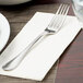 A Libbey stainless steel dinner fork on a white napkin.