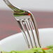 A close-up of a Libbey stainless steel salad fork holding a piece of salad.
