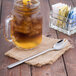A glass jar filled with iced tea with a Libbey Cimarron stainless steel iced tea spoon in it.