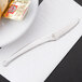 A World Tableware Esquire stainless steel mini knife on a plate with food.