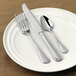 A white plate with a Libbey Geneva stainless steel dinner knife and spoon on it.