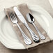 A white plate with a Libbey stainless steel teaspoon and fork on a napkin.