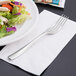 A Libbey stainless steel salad fork on a plate with a salad.