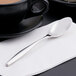 A Libbey stainless steel teaspoon on a napkin next to a black coffee cup.