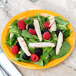 A close-up of a plate of salad with chicken and berries on a yellow Libbey Cantina porcelain plate.