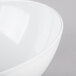 A close up of a white Tablecraft Sierra large round melamine bowl with a curved edge.