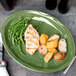 A Libbey sage green oval porcelain platter with chicken, potatoes, and green beans on a table.