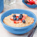 A close up of a Libbey blueberry oatmeal bowl filled with strawberries and blueberries.