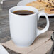 A white Libbey porcelain mug filled with brown coffee sitting on a napkin.