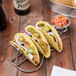 Clipper Mill stainless steel guitar shaped taco holder filled with tacos on a table.