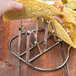 A person holding a taco in a stainless steel guitar shaped taco holder.