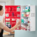 A wall-mounted first aid kit cabinet with multiple shelves and compartments containing various medical supplies.