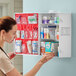 A wall-mounted three-shelf first aid kit cabinet stocked with various medical supplies and medications.