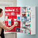 A large wall-mounted first aid kit cabinet with multiple shelves and compartments containing various medical supplies.