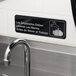 A black and white Tablecraft sign that says "Employees Must Wash Hands Before Returning to Work" on a wall.