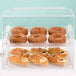 A Cal-Mil clear acrylic display case with donuts and pastries on a counter.