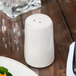 A Libbey Farmhouse ivory porcelain pepper shaker on a table.