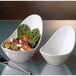 A close-up of a Libbey white porcelain bowl filled with salad with a spoon next to it.