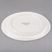A Libbey medium rim porcelain plate in ivory with a logo on it.