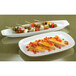 Two Libbey ultra bright white porcelain canoe trays with skewers of vegetables on them.